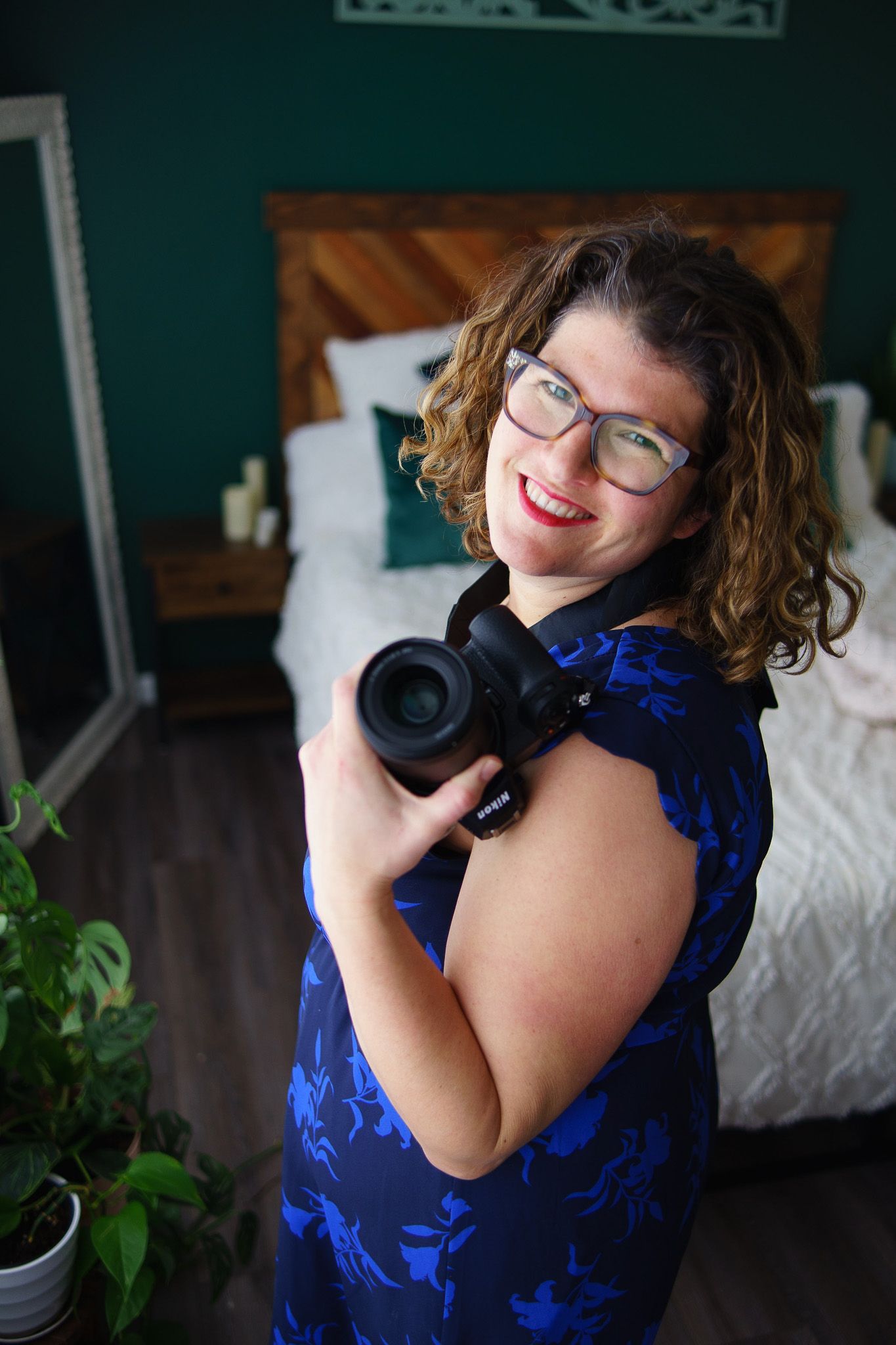 A woman in a blue dress is holding a camera over her shoulder.