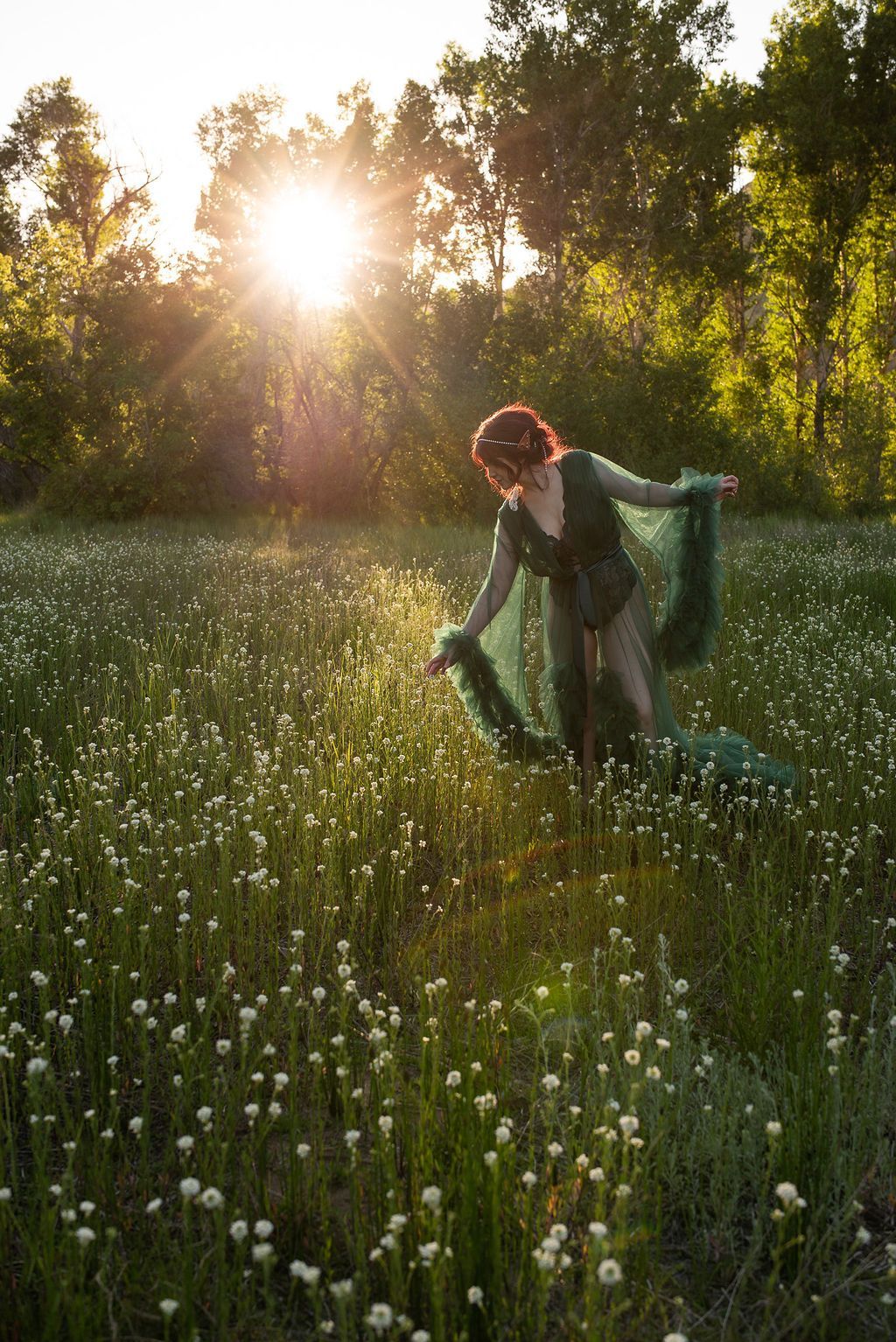 A woman is standing in a field of flowers at sunset.