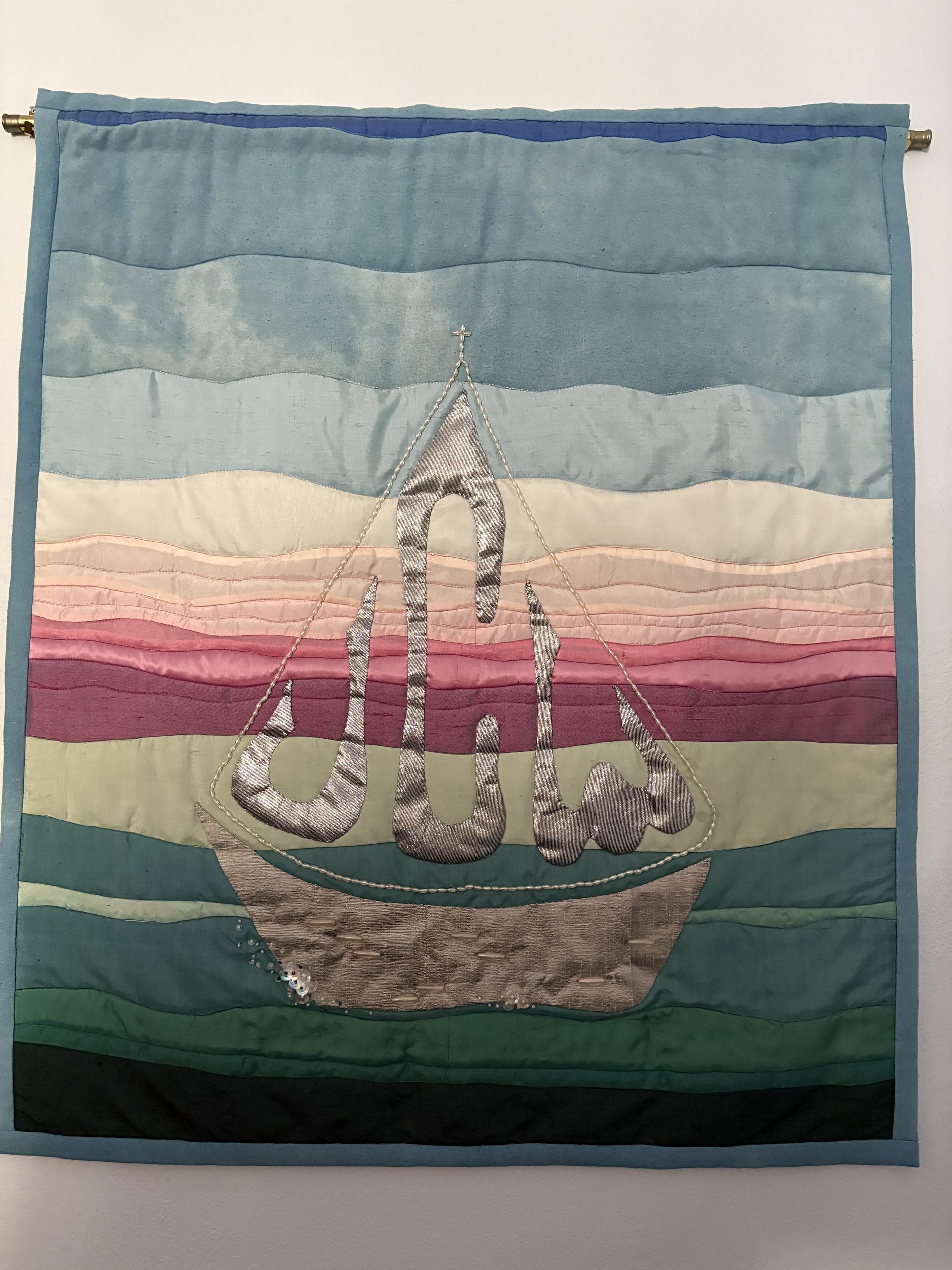 Quilted wall hanging featuring the UCW as sails of a boat over a landscape of color gradients.