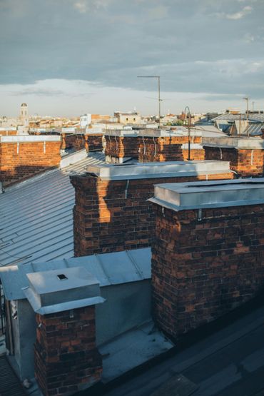 View of rooftops with brick chimneys, in the warm light of dusk.