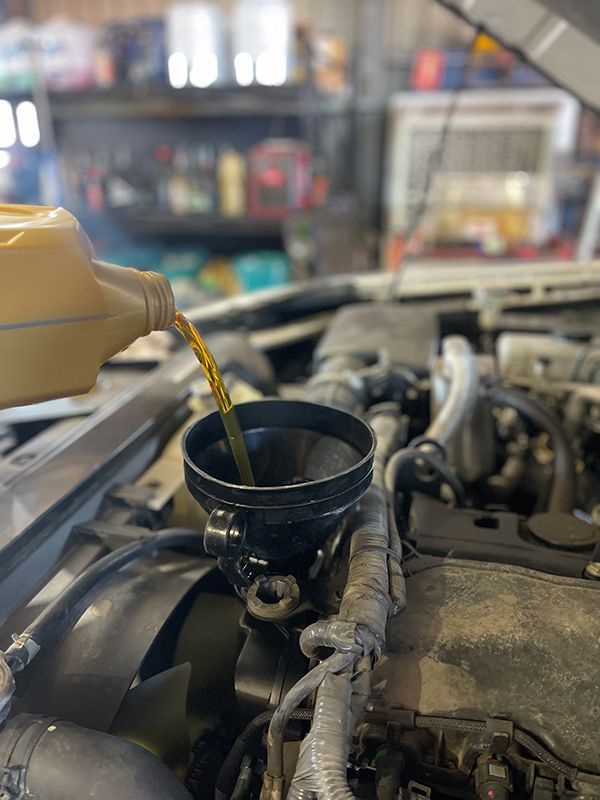 A Person Is Pouring Oil Into A Car Engine — Autocool Air Conditioning in Raymond Terrace, NSW