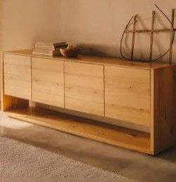 Credenza in legno con libri e oggetti decorativi in ​​una stanza calda e minimalista.