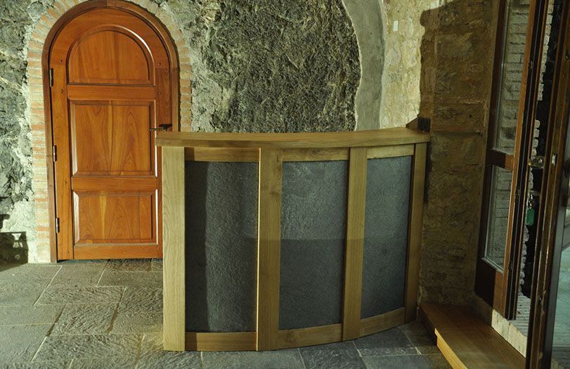 Interno in pietra con porta in legno e bancone o barriera in legno curvato con pannelli in rete scura