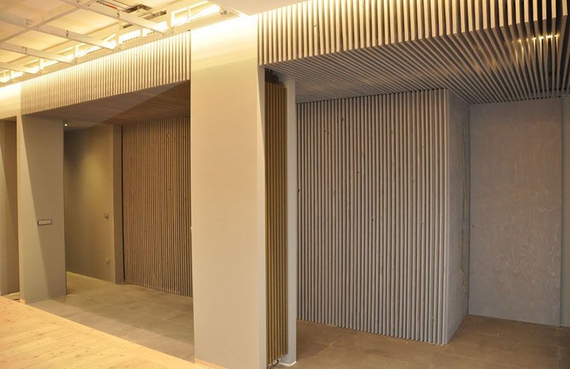 Corridoio beige con pannelli a parete a doghe verticali e illuminazione a soffitto calda.