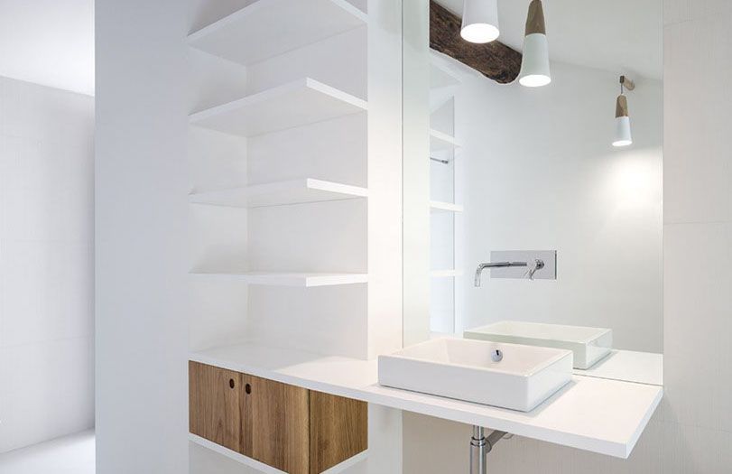 Bagno moderno bianco con mobile sospeso, lavabo, specchio e lampade a sospensione.