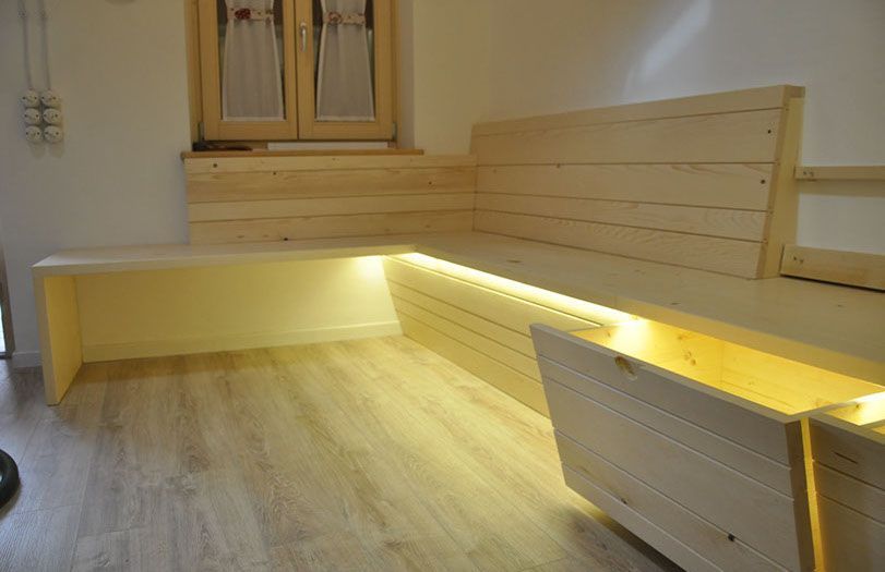 Panchine moderne in legno con illuminazione calda dal basso in una stanza minimalista