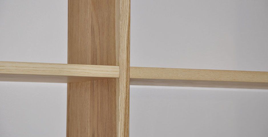Primo piano di una struttura di mensola in legno con traverse in legno chiaro su sfondo grigio chiaro.