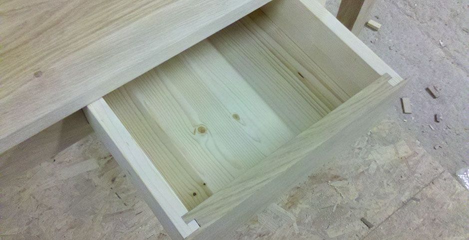 Scatola con cassetto in legno aperta su un banco da lavoro, vista dall'alto.