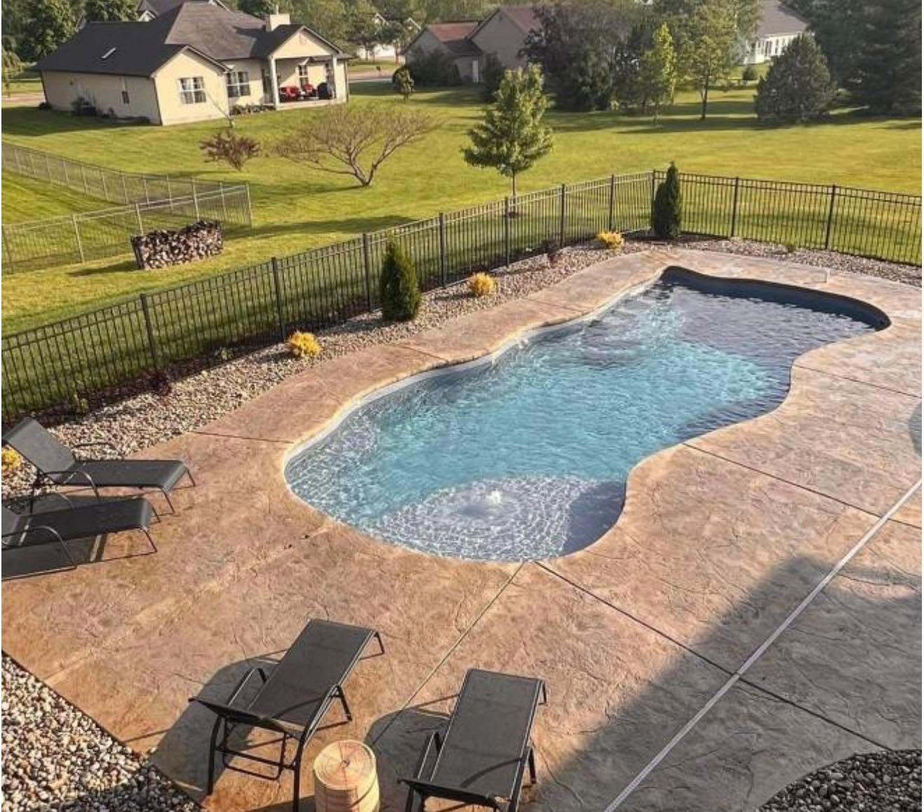 A large swimming pool surrounded by chairs and a fence