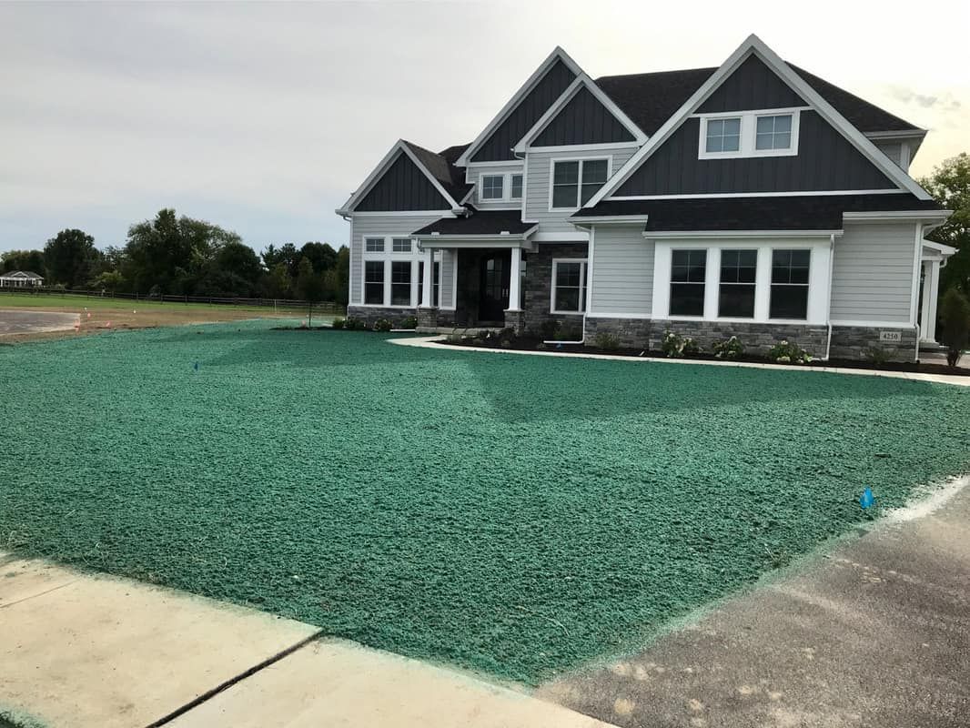 A large white house with a green lawn in front of it.
