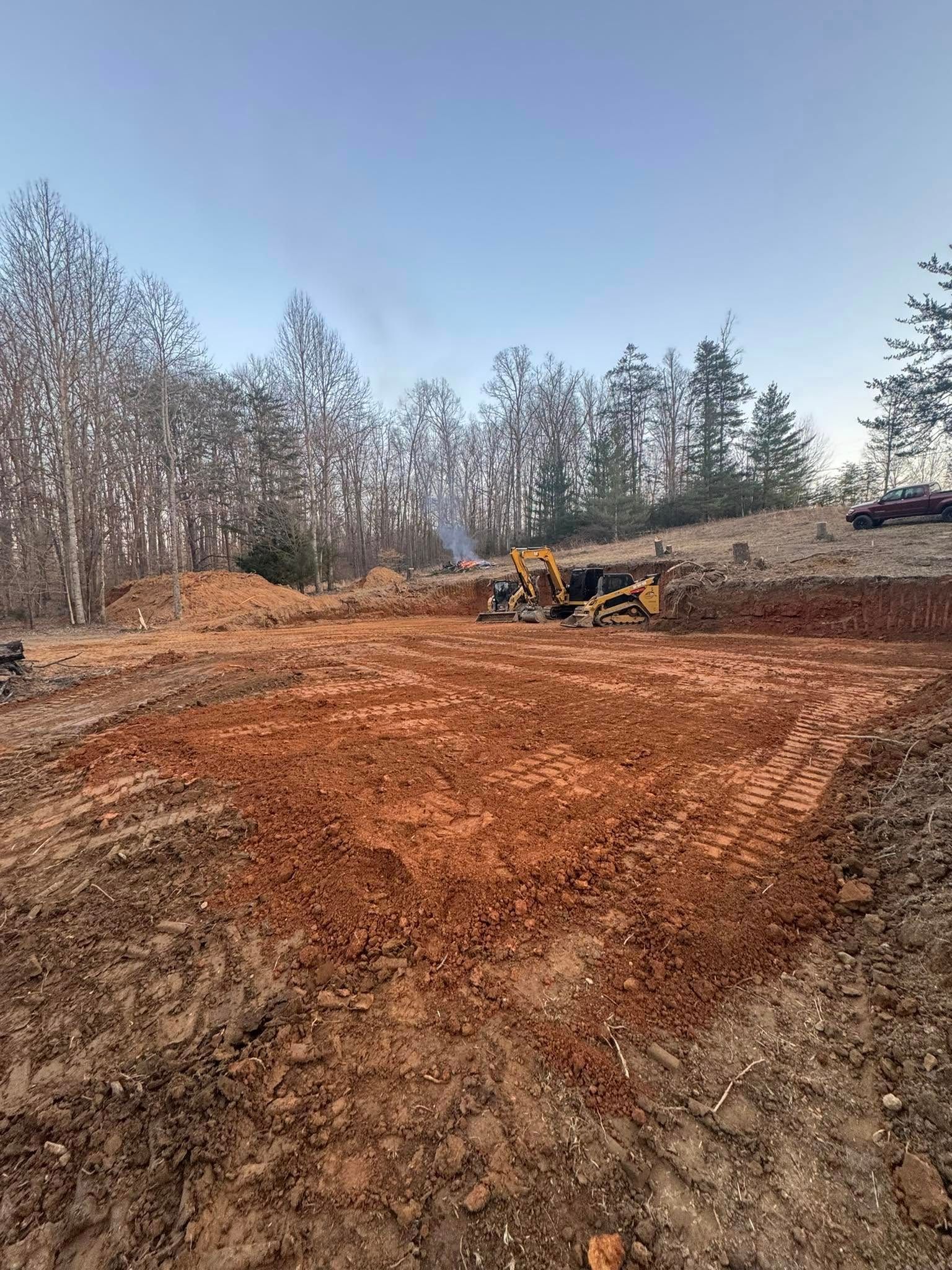 A bulldozer is moving dirt in a field with trees in the background.