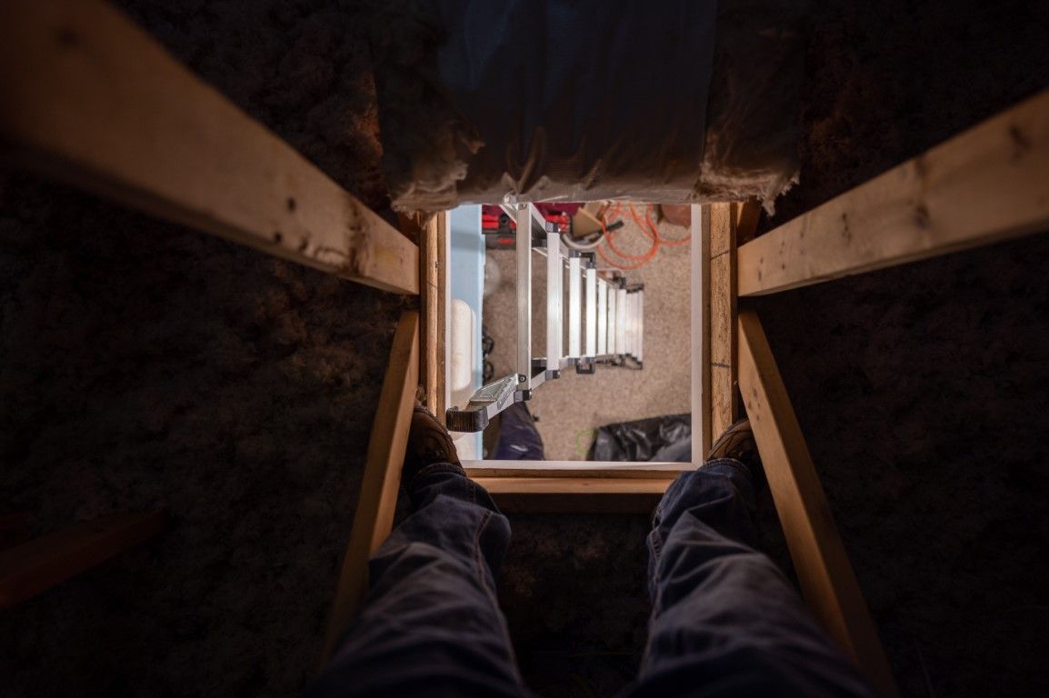Legs inside a narrow wooden tunnel, looking out toward a bright walkway and buildings