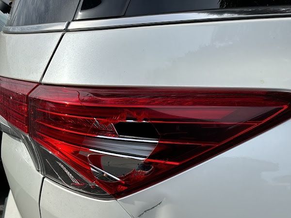Close-up of a silver car’s red rear taillight and body panel