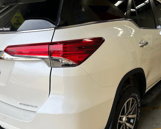 White SUV rear quarter view with red taillight and tinted windows in a showroom