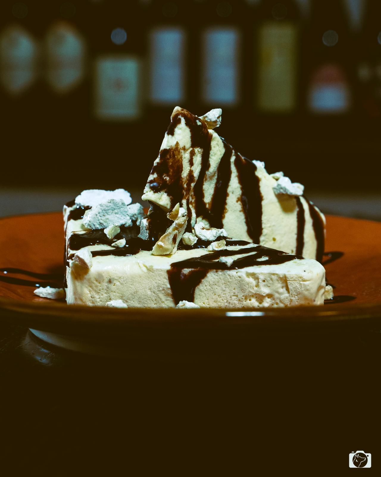 Dessert al gelato con gocce di cioccolato e guarnizioni su un piatto. Sfondo scuro.