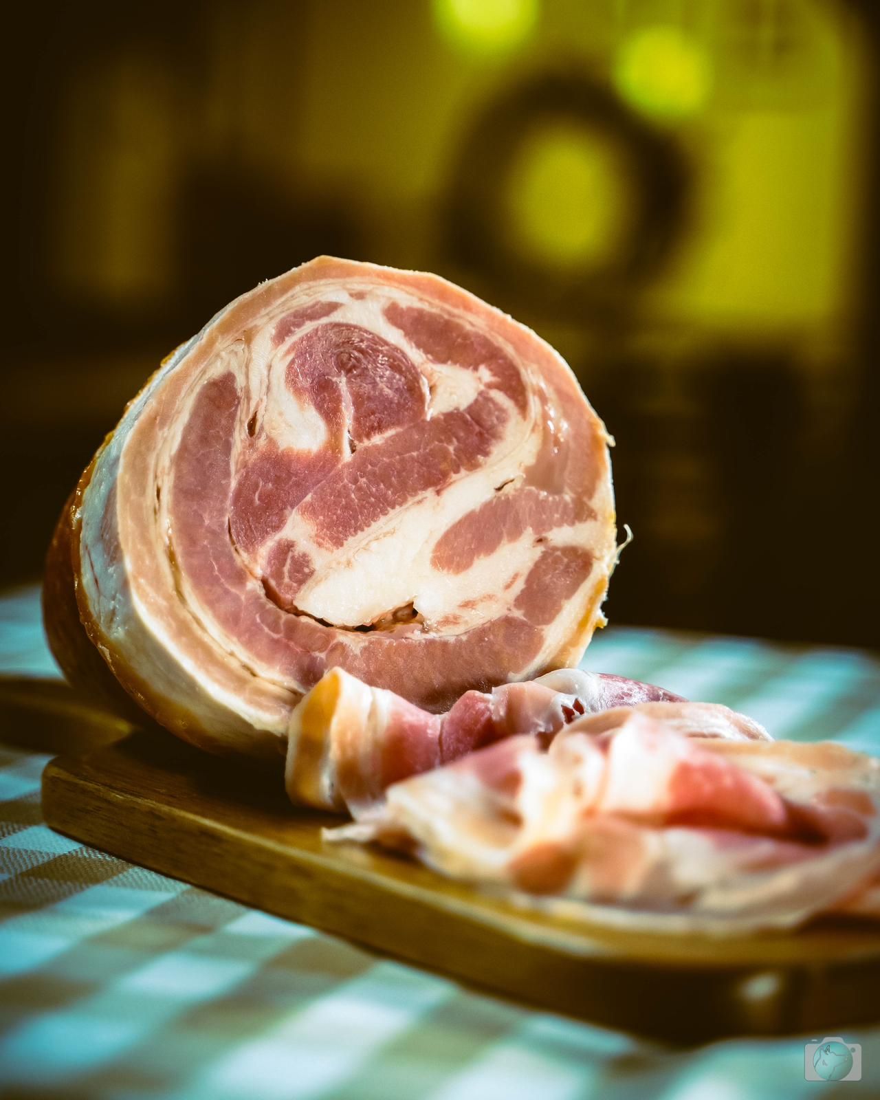 Coppa affettata su un tagliere di legno, con una sezione trasversale visibile della carne arrotolata.