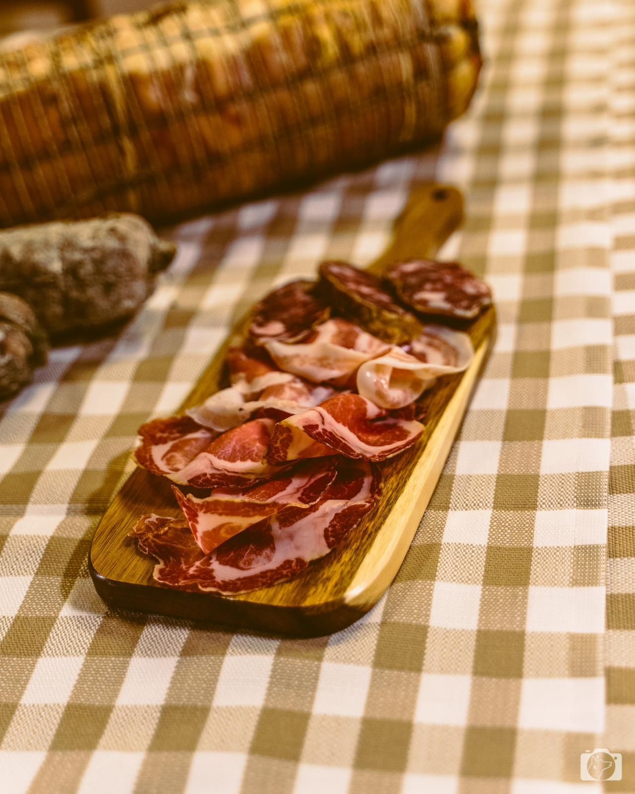Tagliere di salumi con affettati su una tovaglia a quadri.