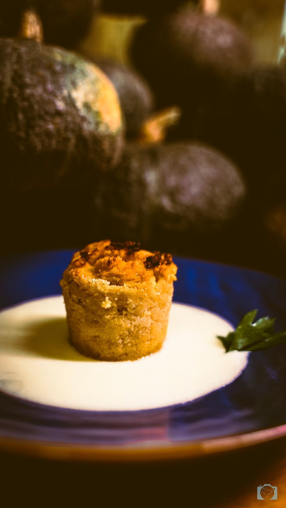 Muffin salato su besciamella, piatto blu. Zucche sfocate sullo sfondo.