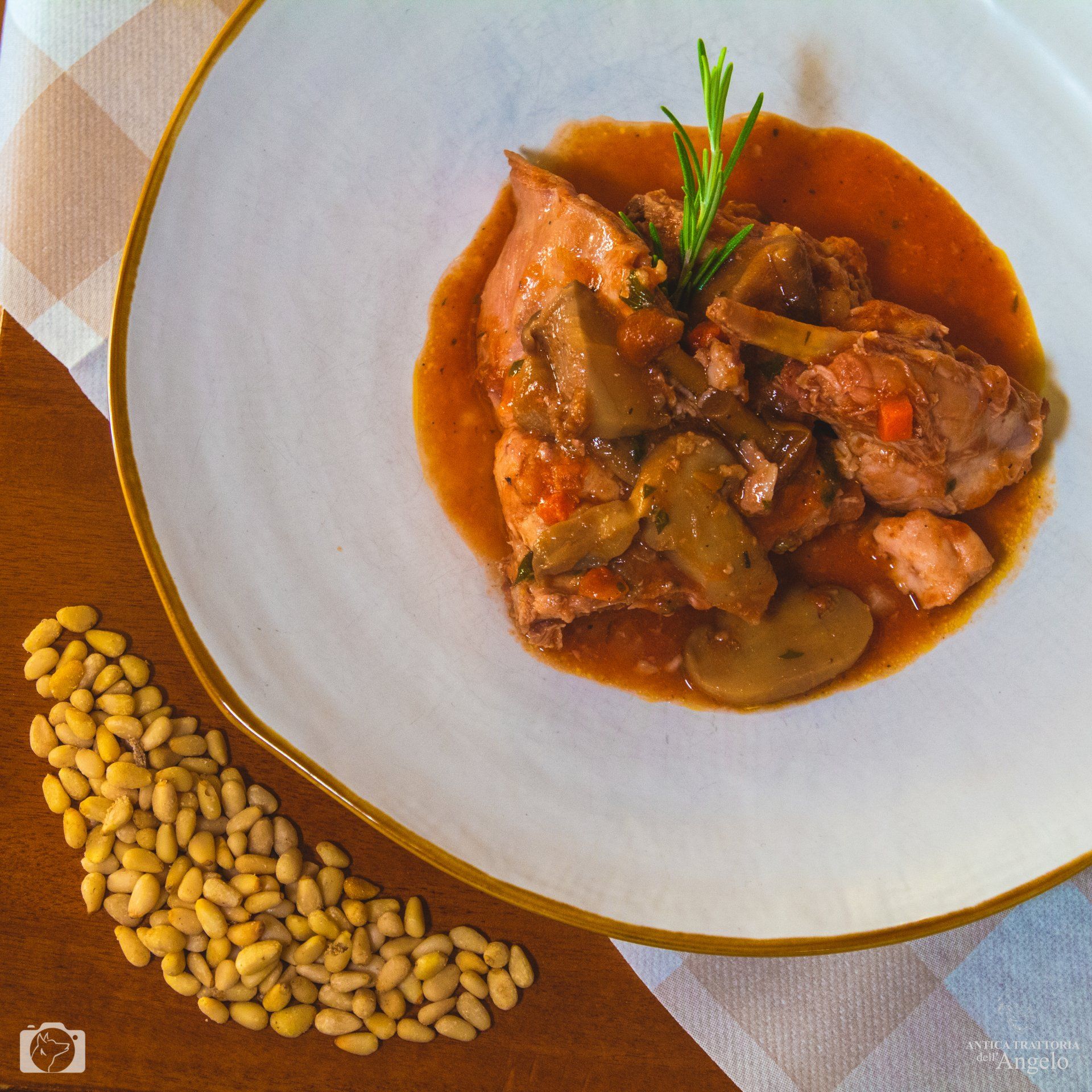 Stufato con funghi, guarnizione di rosmarino, servito su un piatto bianco con pinoli a parte.