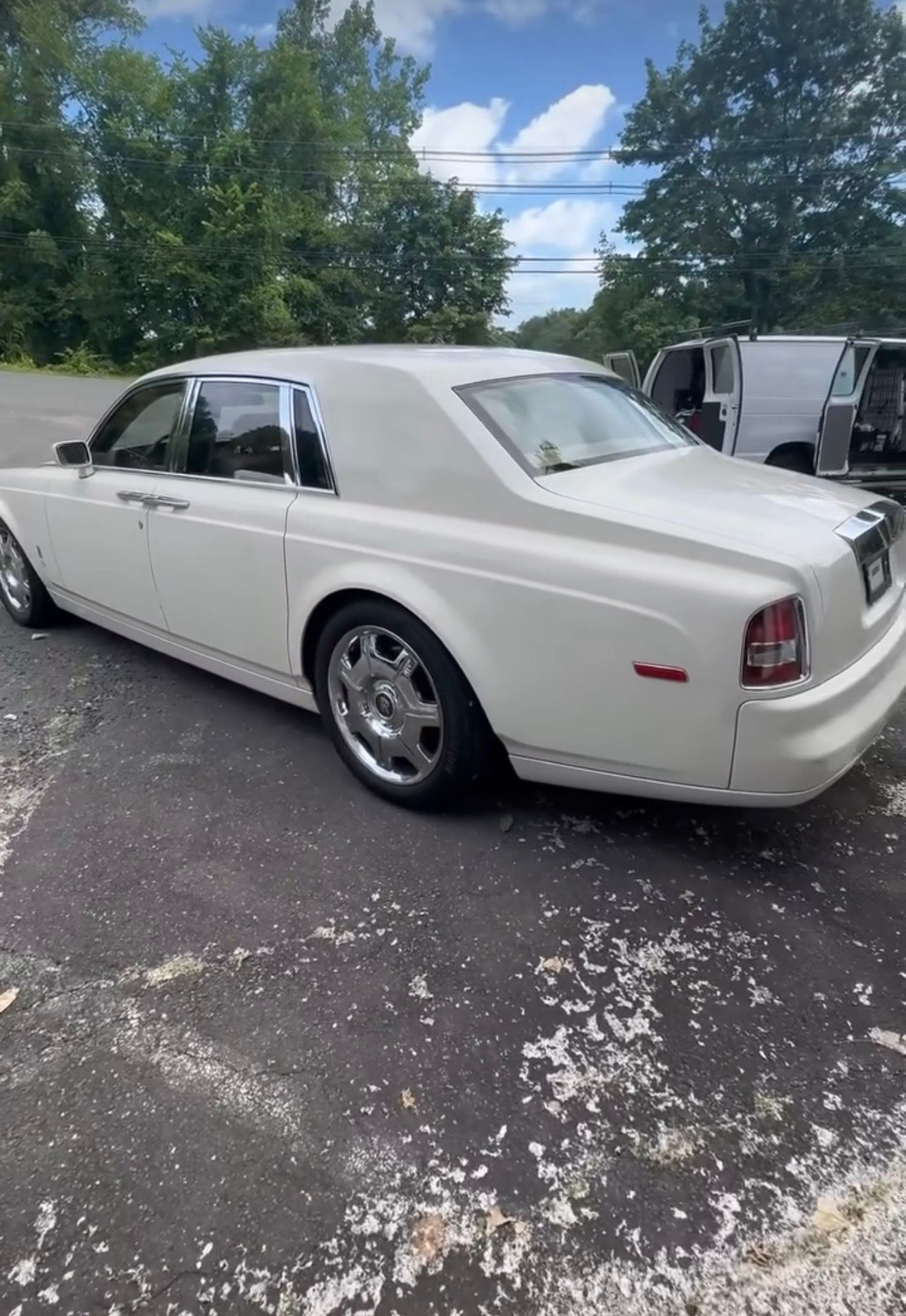 White luxury sedan parked outdoors in a lot, viewed from the rear side