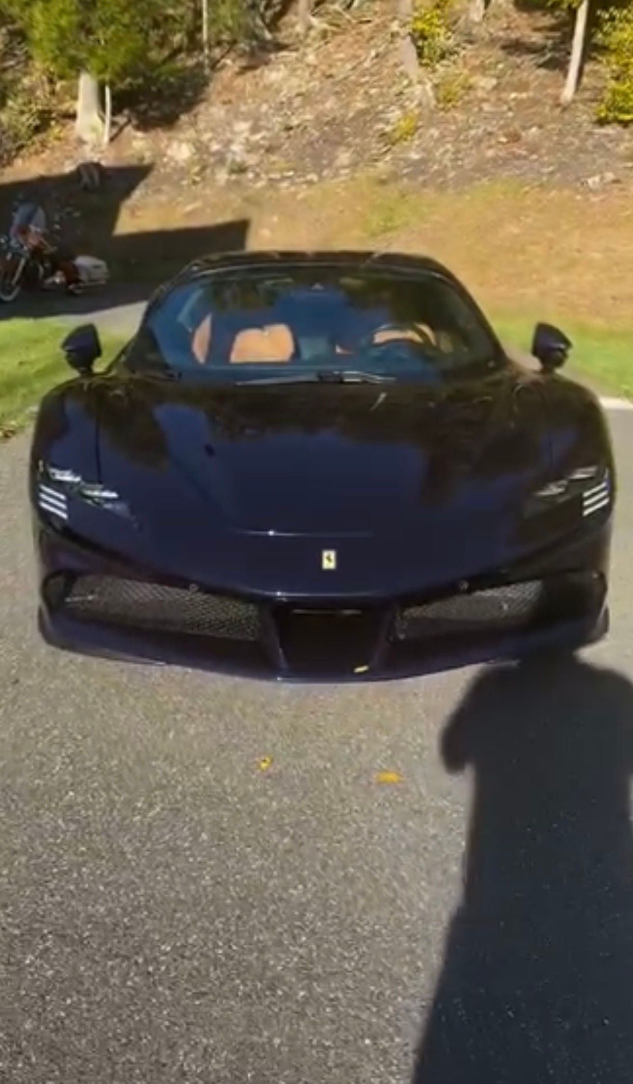 Dark blue Ferrari sports car parked on a driveway in sunlight