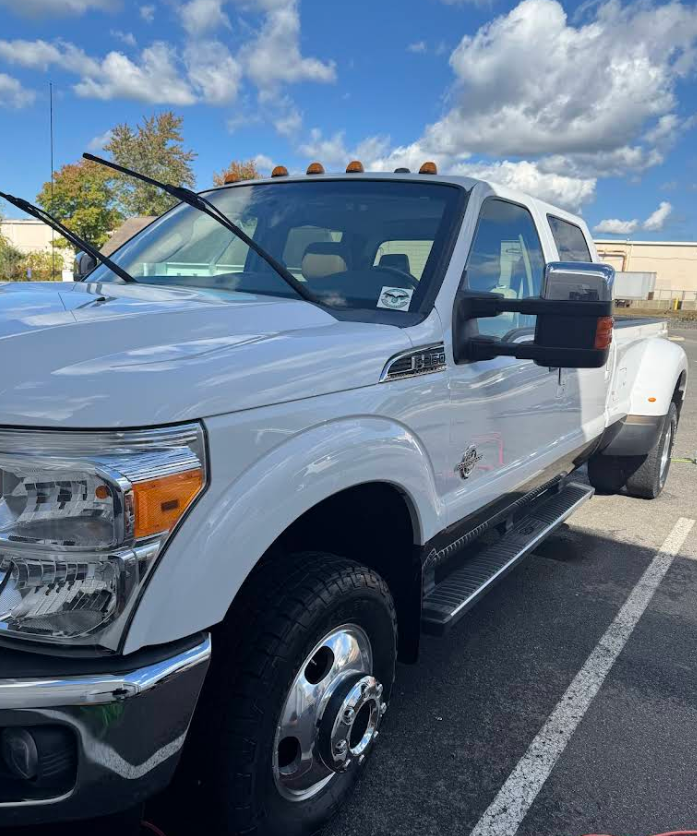 A white truck is parked in a parking lot on a sunny day.