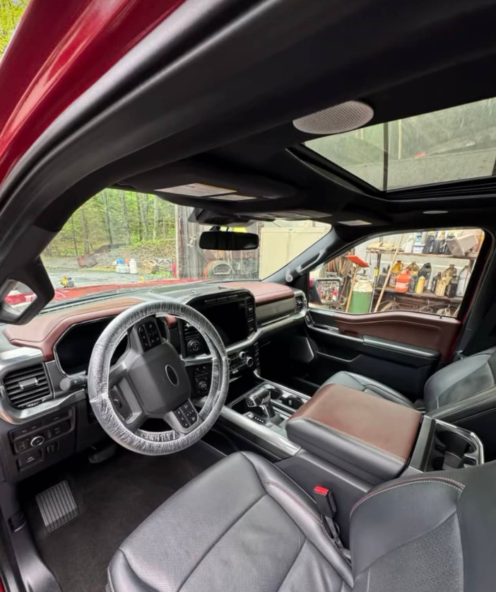 The inside of a red truck with a sunroof.