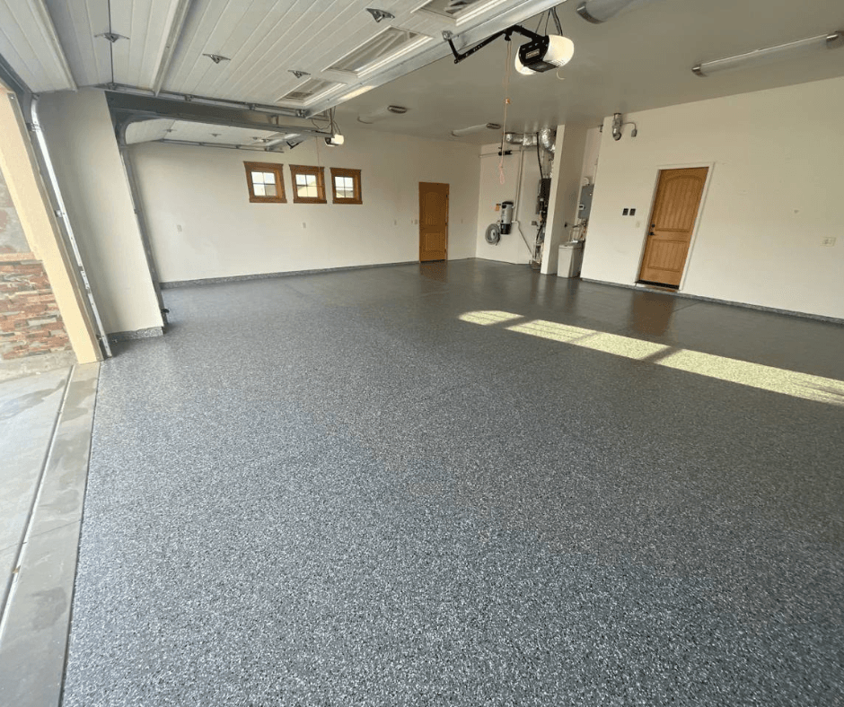 Empty garage with speckled epoxy floor, white walls, two doors, and overhead lights.