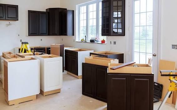 Kitchen renovation with dark cabinets, white islands, and boxes in a bright room