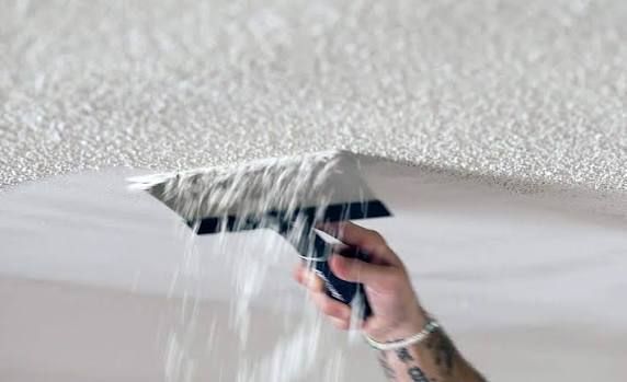 Hand sanding a white wall/ceiling with a pole sander, removing paint or texture dust