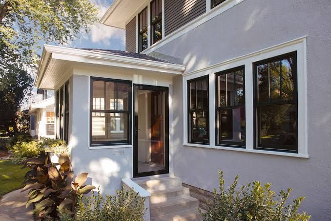 Modern house exterior with white stucco walls, black-trimmed windows, and a small covered front entry.