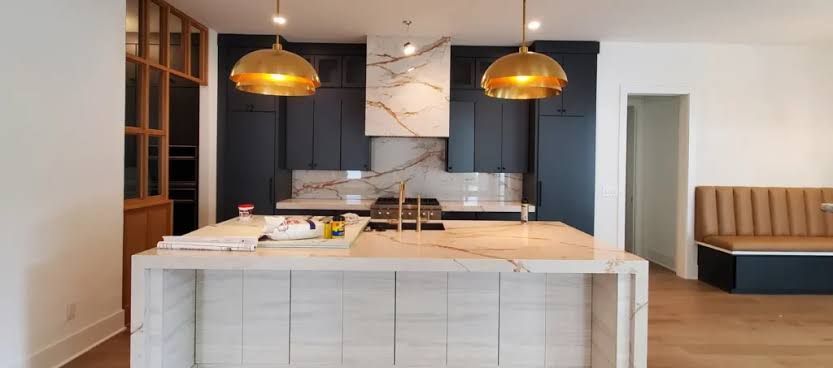 Modern kitchen with white island, dark cabinets, and two copper pendant lights