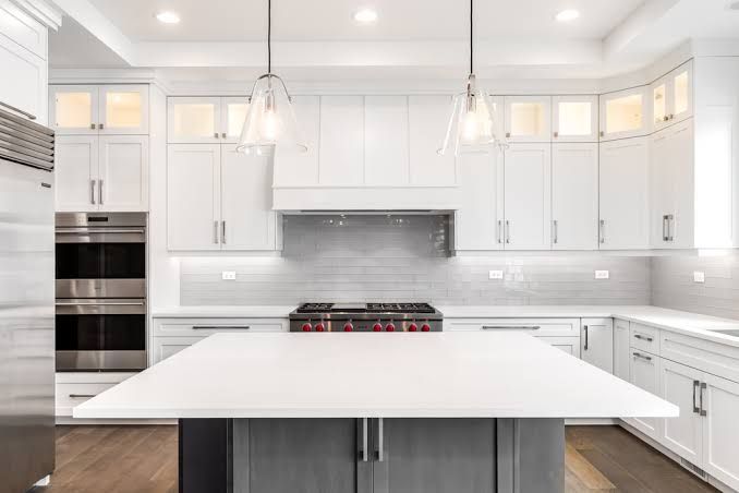 Bright white modern kitchen with large island, pendant lights, and built-in stainless steel appliances