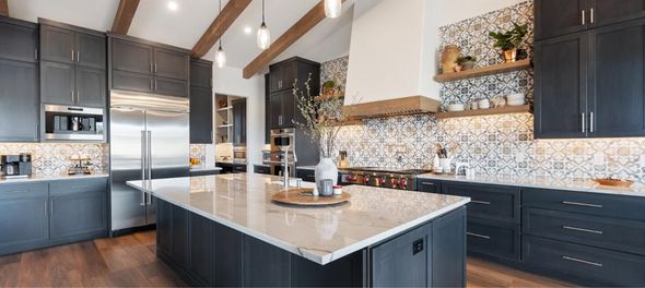 Modern kitchen with dark cabinets, large island, stainless appliances, and mosaic backsplash