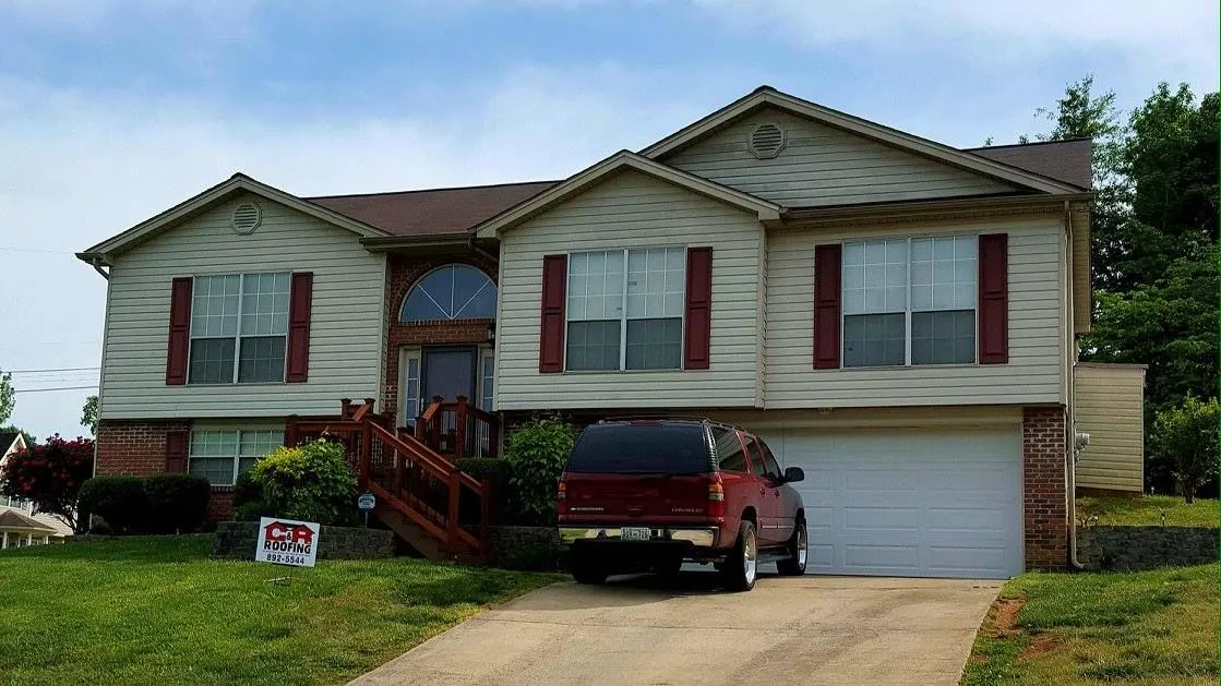 Two-story house with beige siding, red shutters, and a red truck parked in front of the garage.