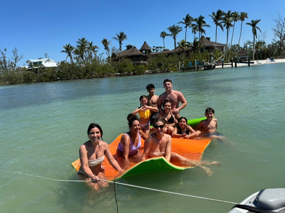 Group of people riding a colorful inflatable on calm tropical water near palm trees