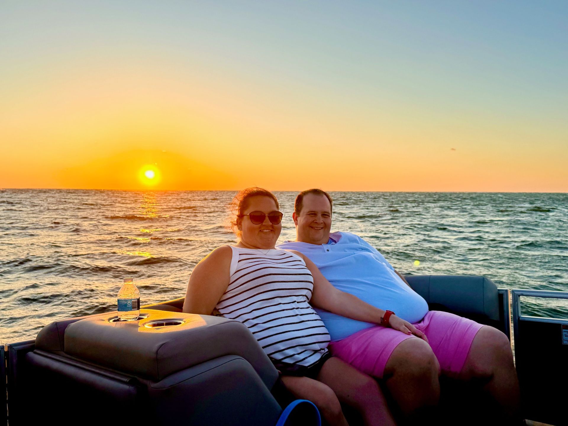 Two people sitting on a boat at sunset on open water