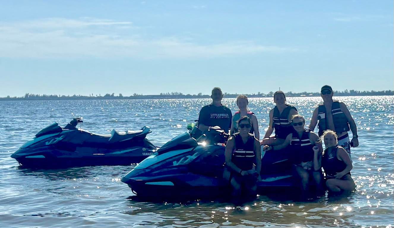 Group on jet skis in shallow water by a sunny shoreline