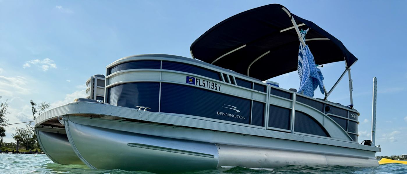 Pontoon boat with blue canopy floating on calm water under a clear sky