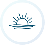 Sunrise over water, with sun's rays radiating from the upper half of the sun.