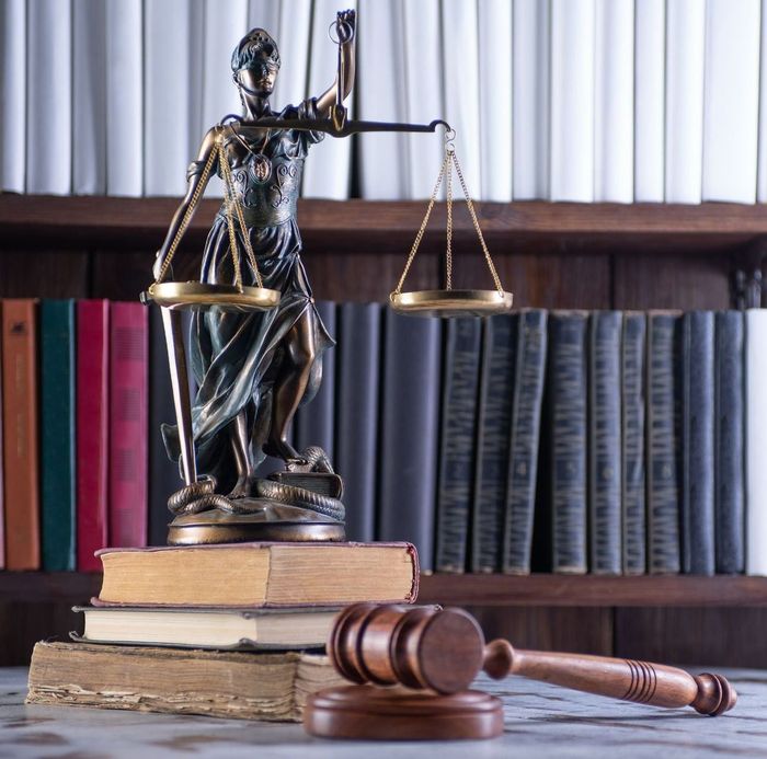 una statua di giustizia è seduta sopra una pila di libri