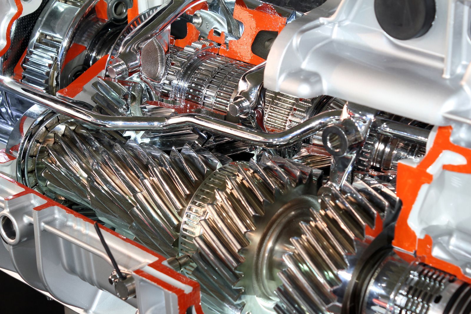 Cutaway of a car transmission with shiny metal gears and orange-highlighted components