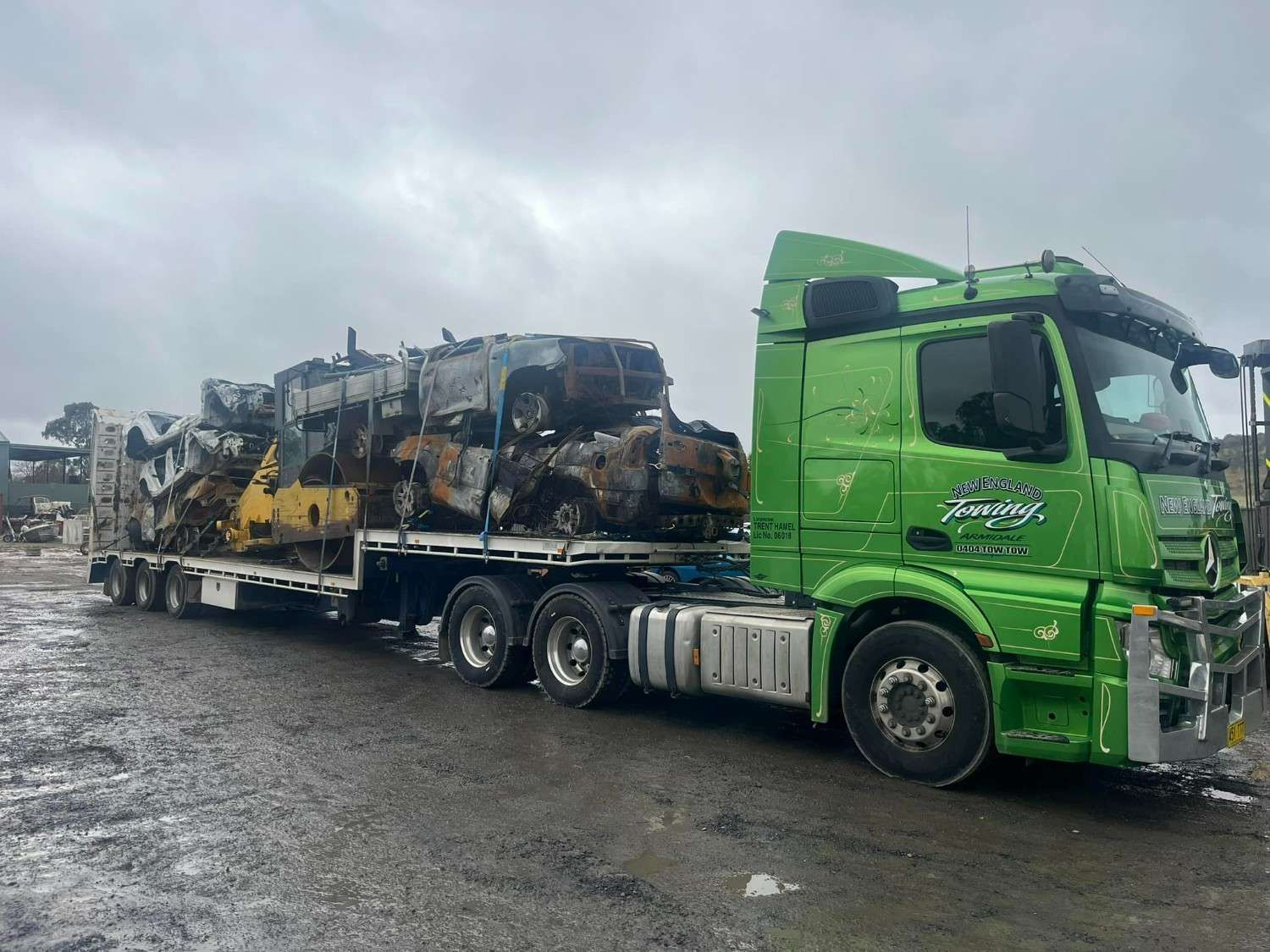 A Green Semi-Truck Hauls a Flatbed Trailer Loaded with Crushed and Scrapped Vehicles — New England Towing in Warialda, NSW
