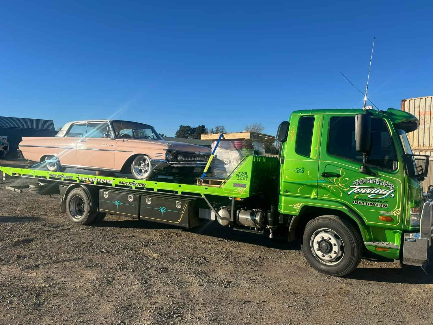 A Light Green Tow Truck Carrying a Pink Classic Car — New England Towing in Guyra, NSW