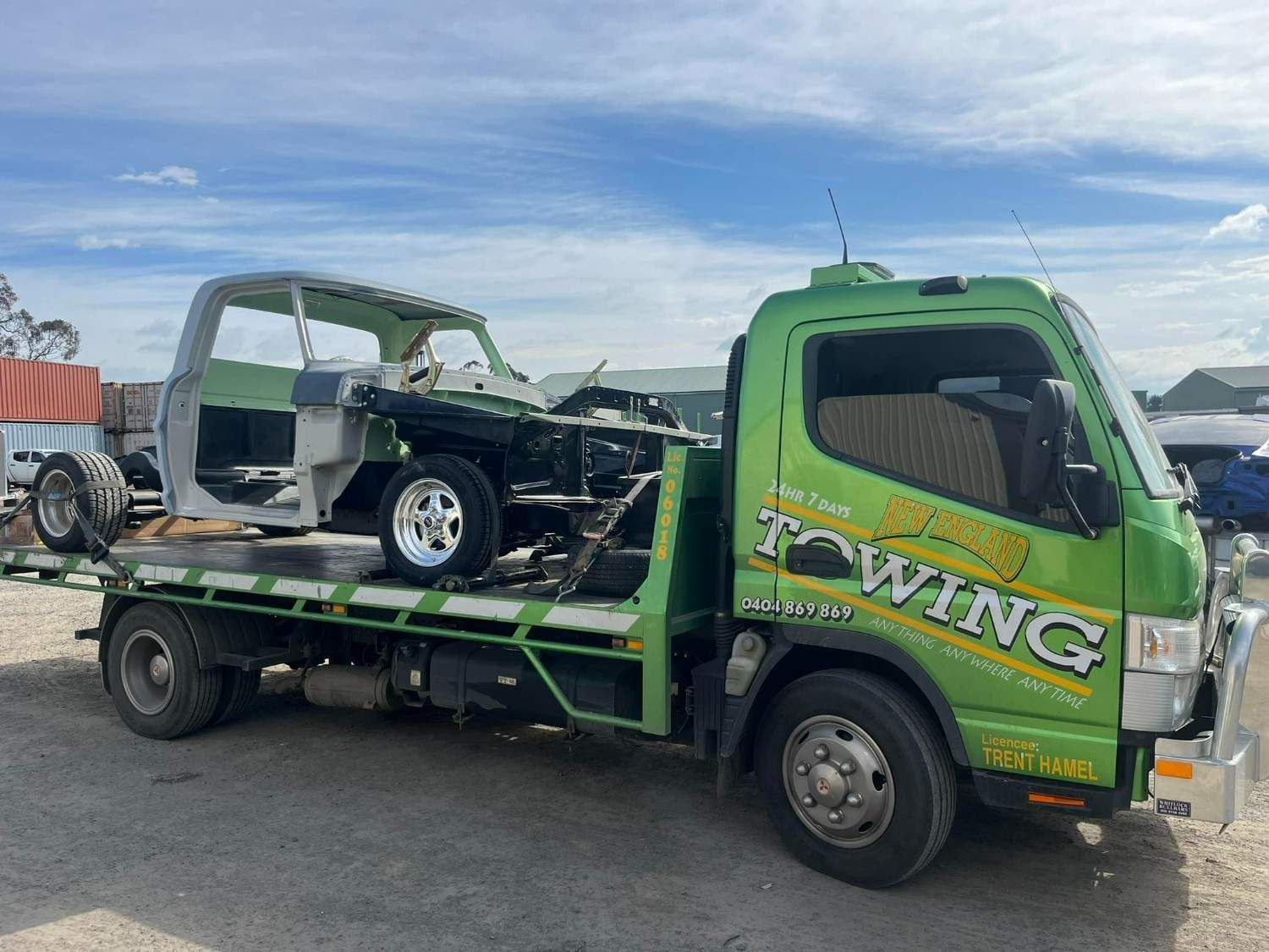 Green Tow Truck Hauling the Stripped Body of A Vintage Pickup Truck — New England Towing in Inverell, NSW