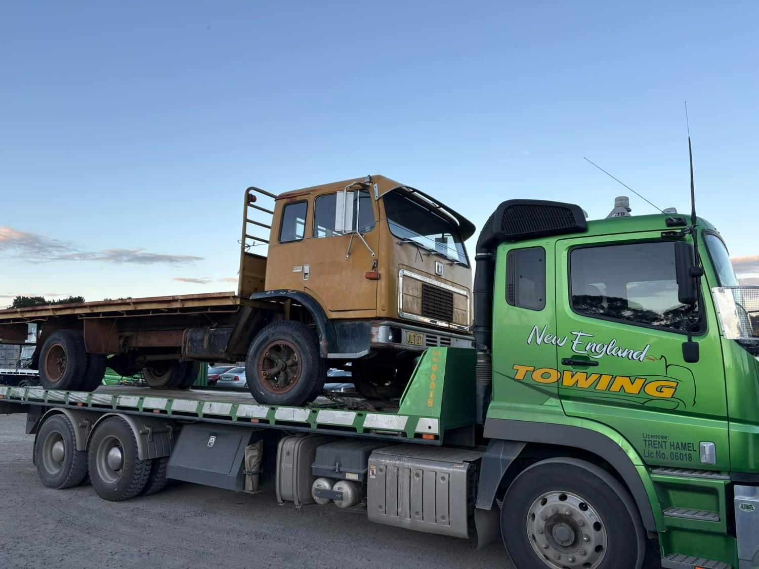 A Vintage Brown Truck Being Transported on A Green Tow Truck — New England Towing in Walcha, NSW