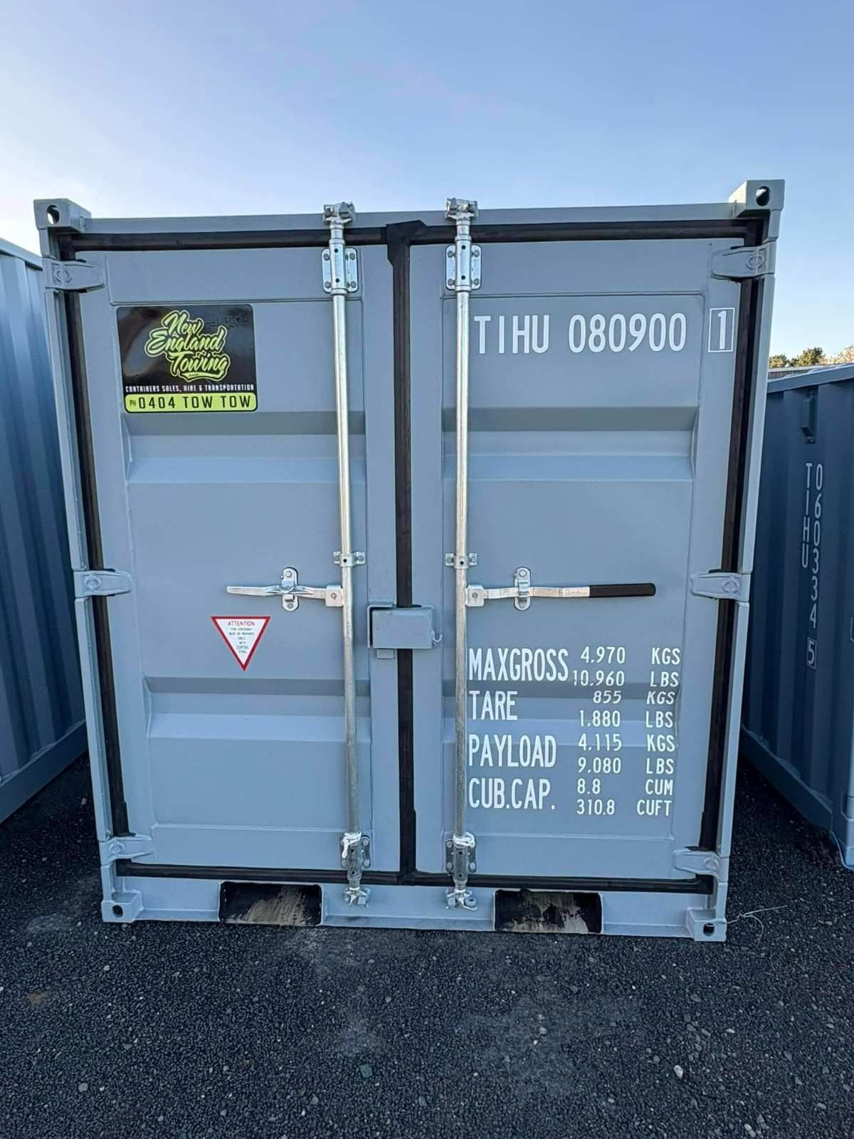 A Gray Shipping Container with Closed Doors and White Markings, Set Outdoors — New England Towing in Ebor, NSW