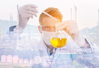 A scientist is holding a beaker of liquid and a pipette.