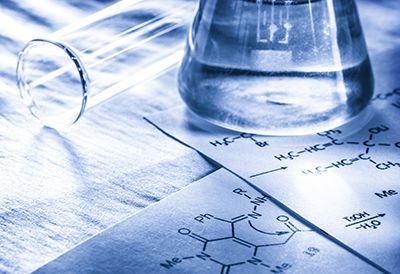 A beaker filled with liquid is sitting on top of a chemical formula.