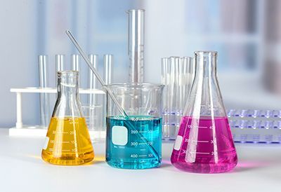 Three beakers filled with different colored liquids are sitting on a table in a laboratory.